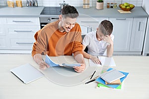 Dad helping his son with homework in kitchen