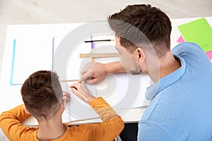 Dad helping his son with homework in room