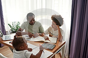 Dad helping son with homework while girl drawing