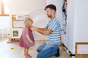 Dad is helping toddler daughter to get dressed
