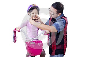 Dad helps his child to fasten helmet