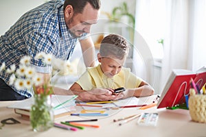 Dad helps his son to do homework. home schooling, home lessons. outside school classes with parents. father examines with his son