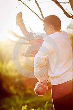 Dad helps support the boy hanging on the branch of a tree, suns