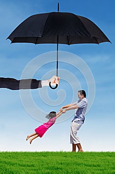 Dad and his daughter playing under umbrella at field