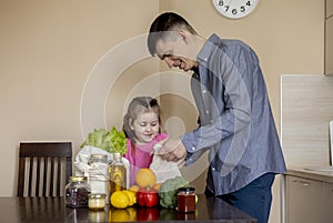 Dad and his daughter are pulling food out of the bag. Purchases from the store. Reusable package