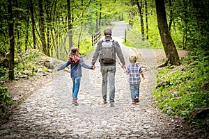 Dad with his kids walks from behind in the woods photo