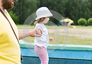 Dad and his little daughter on a walk in the park. A father holds the hand of his little girl in the open air. The concept of fami