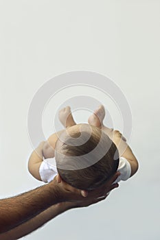 Dad holding 6-month-old baby boy against the white background. Father picking up his baby. Copy space. Family concept