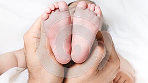 Dad is holding the baby`s tiny feet. Small baby feet on male hands close up. Happy family concept. Beautiful conceptual image of