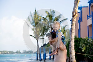 Dad, holding little toddler boy with binoculars, observing dolphins