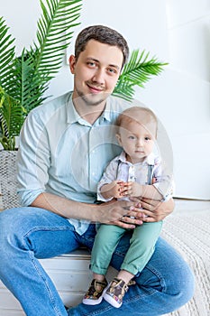 Dad holds a child in his arms and looks at the camera, the concept of a happy family, father`s Day, father-son relationship