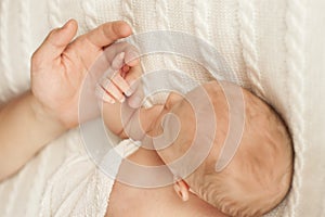 Dad holds her newborn daughter by the hand