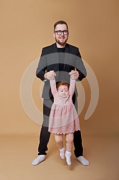 Dad holds his little daughters hands. A man plays with a girl. Family holidays