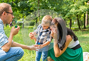 Dad holds his son`s hand and teaches him to blow soap bubbles. M