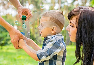 Dad holds his son`s hand and teaches him to blow soap bubbles. M