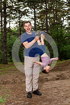 Dad holds his son`s legs upside down. Father-son relationships, Father`s Day, family relationships and love