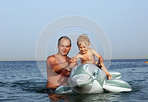 Dad holds the little boy on a toy Dolphin