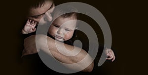 Dad hugging and kissing his baby on the black background. Love and care of father for baby concept