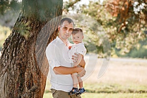 Dad hugging son outdoors in the park. The concept of summer holiday. father`s, baby`s day. Family spending time together on natu