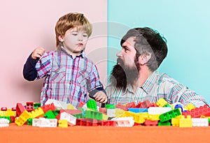 Dad and kid build plastic blocks. Child care development. Family leisure. Father and son create constructions. Bearded photo