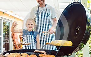 Dad and kid doing the barbeque at the grill