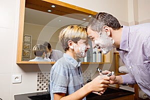 Dad and kid smiling during shaving touch foreheads hold razors