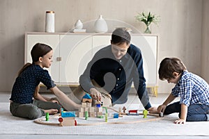 Dad and kids play toy railroad at home