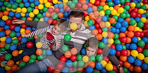Dad and kids playing in pool with colorful balls