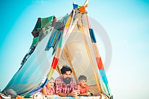 Dad with kids playing together in tent. Summer outdoor. Family playing together. Happy father with chidren, camping