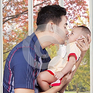 Dad kiss male baby at home