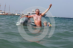 Dad and the little boy swimming near the toy Dolphin