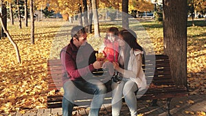 Dad, little daughter and mom play in autumn park on bench. concept of happy childhood. baby, mother and father are