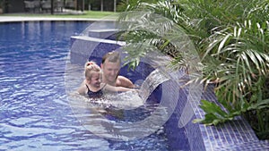 Dad with a little daughter swim in the pool.