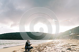 Dad with a little girl flying a kite sitting on the beach by the sea