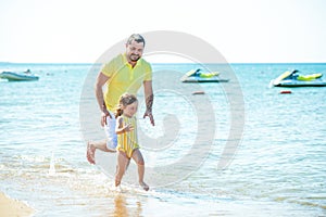 Dad and little girl play, run on the beach and fool around on the sea coast. Family vacation at sea with a child