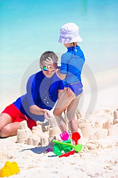 Dad and little girl playing with beach toys on