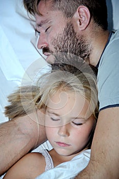 Dad and little girl sleeping together on bed