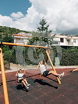 Dad and little girl swing on chain swings at the playground