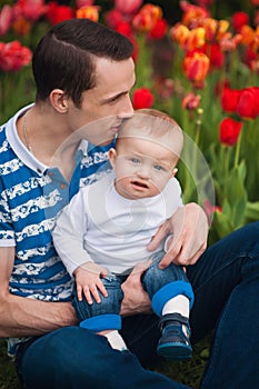 Dad and little son play together outdoors in spring park. Father`s day.