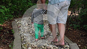 Dad with little son walking through healthy foot barefoot massage path