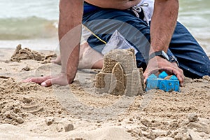 Dad makes a sand castle on the beach