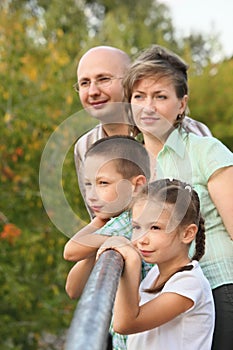 Dad, mom, boy and girl is lean elbow on bridge