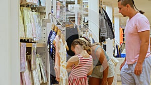 Dad and mom with her little child shopping shirt in clothing store.Happy loving family choose looking for clothes in