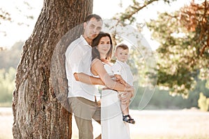 Dad, mom hugging son outdoors in the park. The concept of summer holiday. Mother`s, father`s, baby`s day. Family spending time