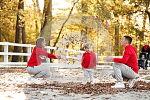 Dad, mom and little cute daughter having fun and playing with leaves in the autumn park. family concept, father`s, mother`s and