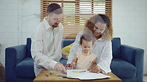 Dad, Mom and little daughter drawing with colorful pencils on paper happy smiling.Young family spend free time together in living