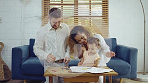 Dad, Mom and little daughter drawing with colorful pencils on paper happy smiling.Young family spend free time together in living