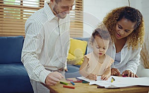 Dad, Mom and little daughter drawing with colorful pencils on paper happy smiling.Young family spend free time together in living