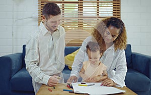 Dad, Mom and little daughter drawing with colorful pencils on paper happy smiling.Young family spend free time together in living