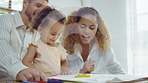 Dad, Mom and little daughter drawing with colorful pencils on paper happy smiling.Young family spend free time together in living